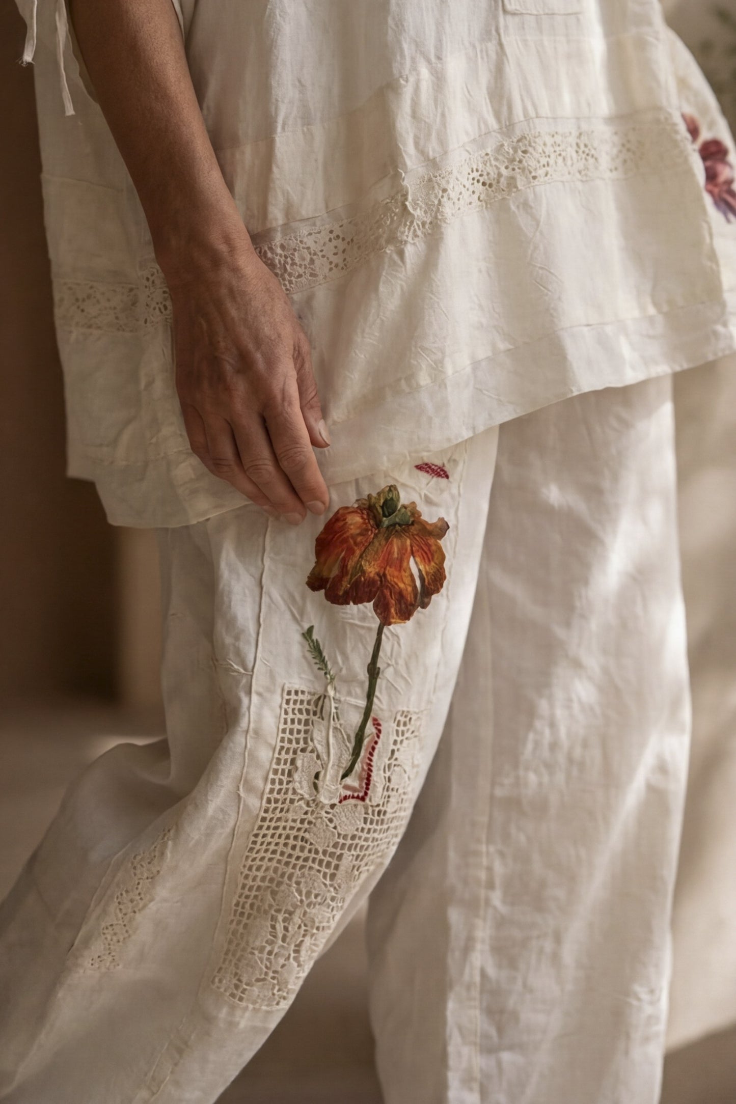 Pantalone écru con applicazioni floreali e inserti crochet