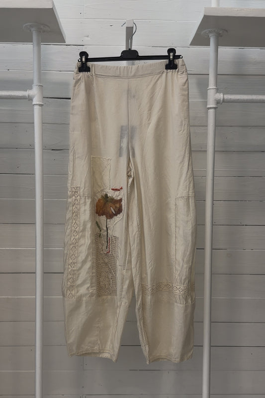 Pantalone écru con applicazioni floreali e inserti crochet